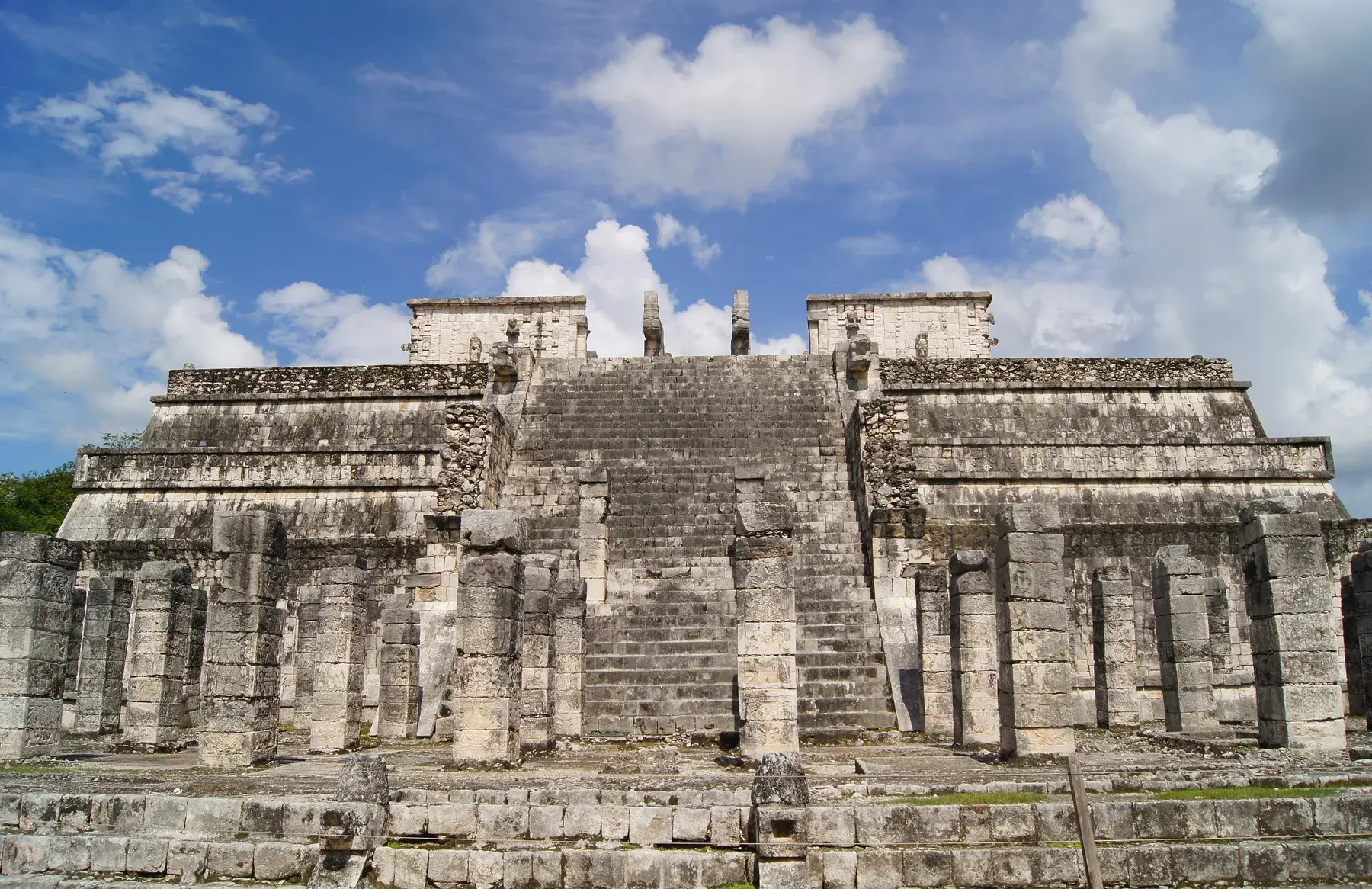 Temple of the Warriors at Chichén Itzá, with stone columns and a central staircase under a cloudy sky