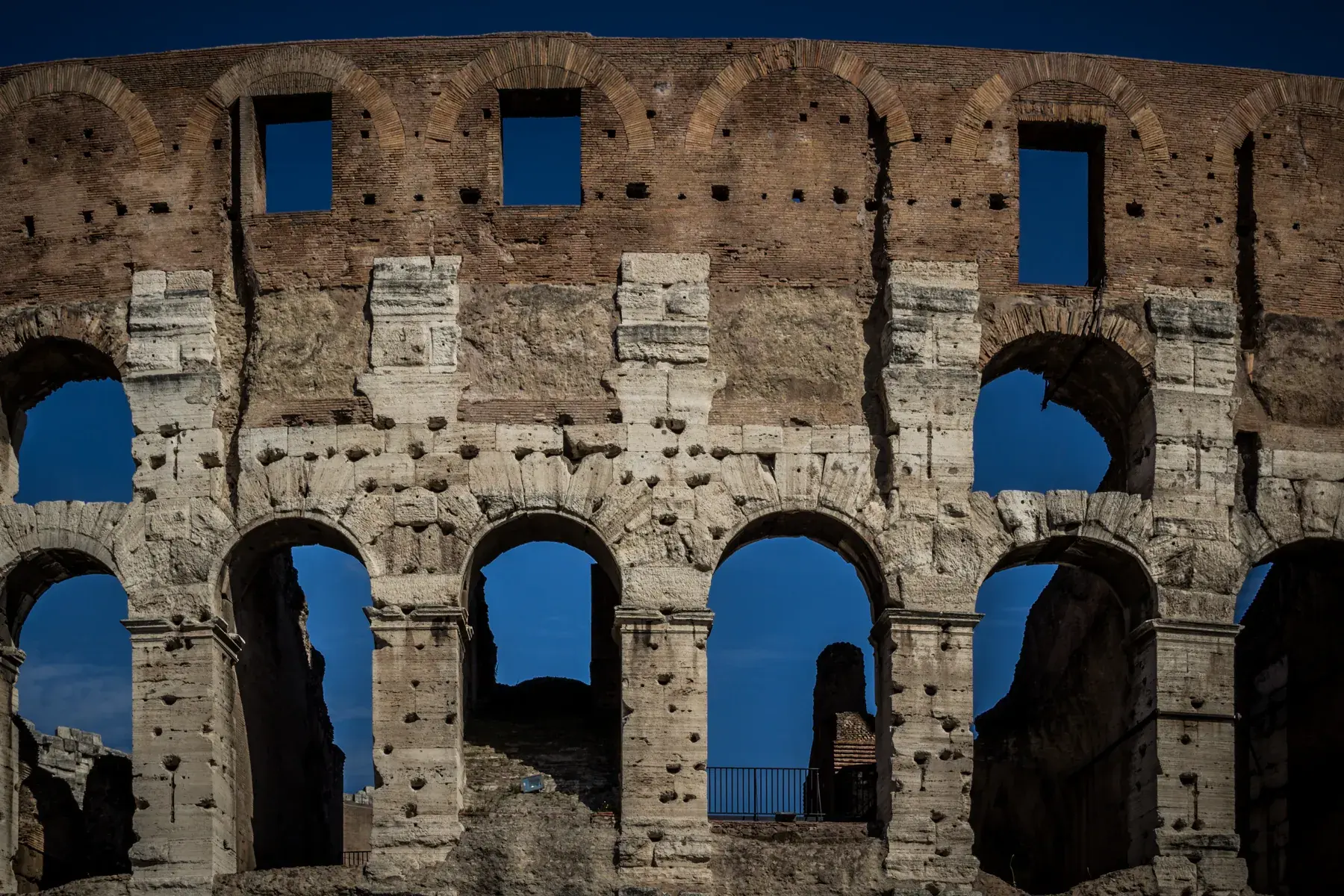 Detail of the travertine arcades of the Colosseum’s outer ring against the blue sky