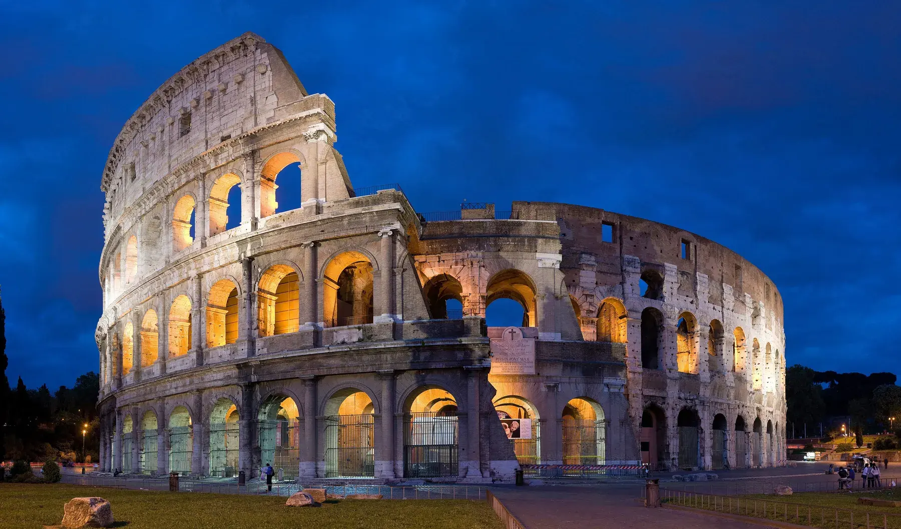Colosseum illuminated at blue hour, with its arcades lit up against the dark blue sky