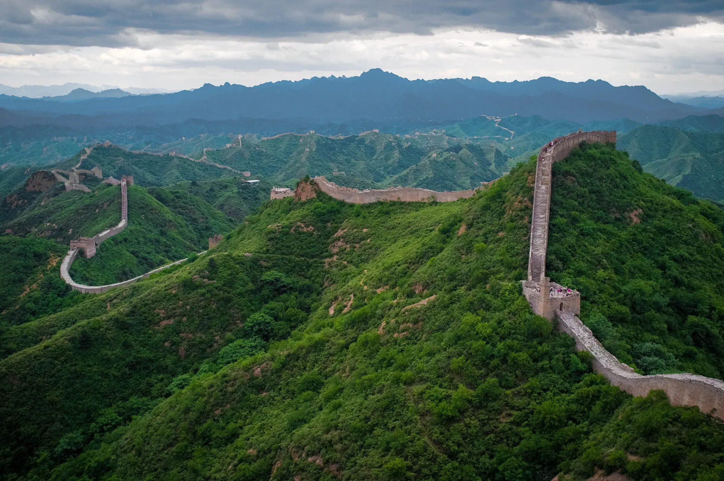 Great Wall of China winding along green ridges at Jinshanling, with watchtowers and mountains in the background