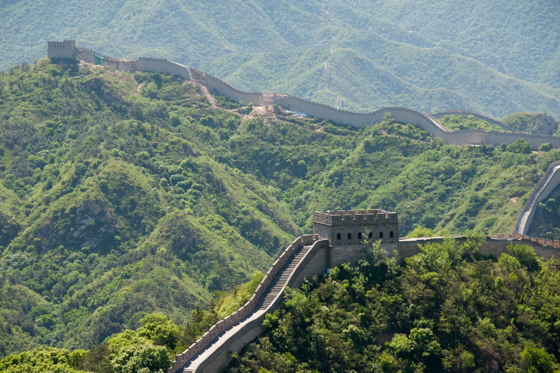 Badaling section of the Great Wall of China climbing wooded slopes up to a watchtower