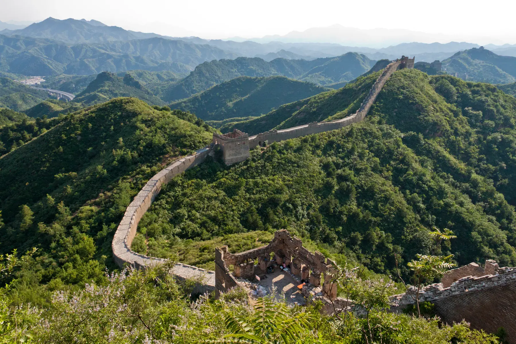 Great Wall of China running along vegetation-covered mountain ridges to the horizon at Jinshanling
