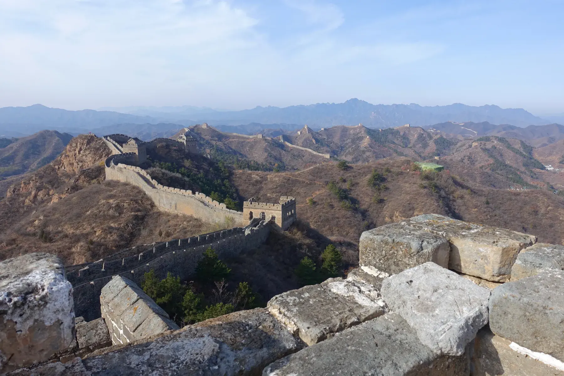 Great Wall of China at Jinshanling seen from the top of a tower, with stone blocks and layers of mountains in the background