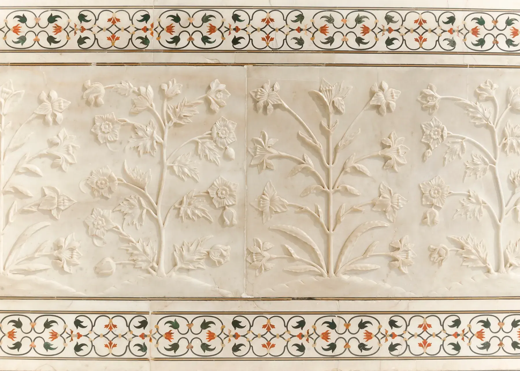 Floral reliefs in white marble and pietra dura friezes with inlaid colored stones at the Taj Mahal